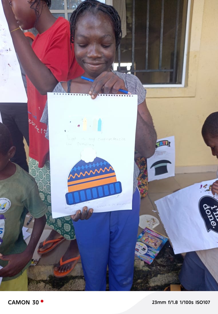 A child proudly displaying her artwork at a creativity workshop